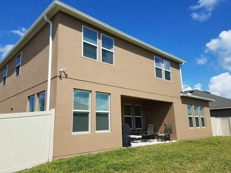 Rear tan stucco two story white gutters vinyl fence covered patio, Sanford